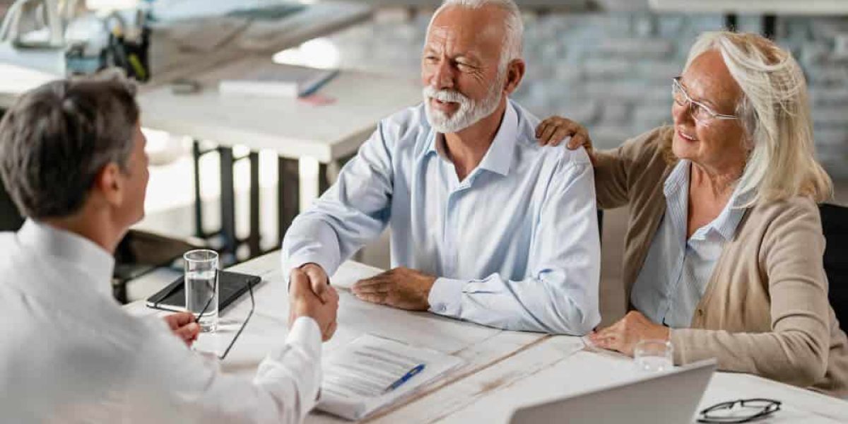 Happy senior couple shaking hands with insurance agent after successful agreement meeting